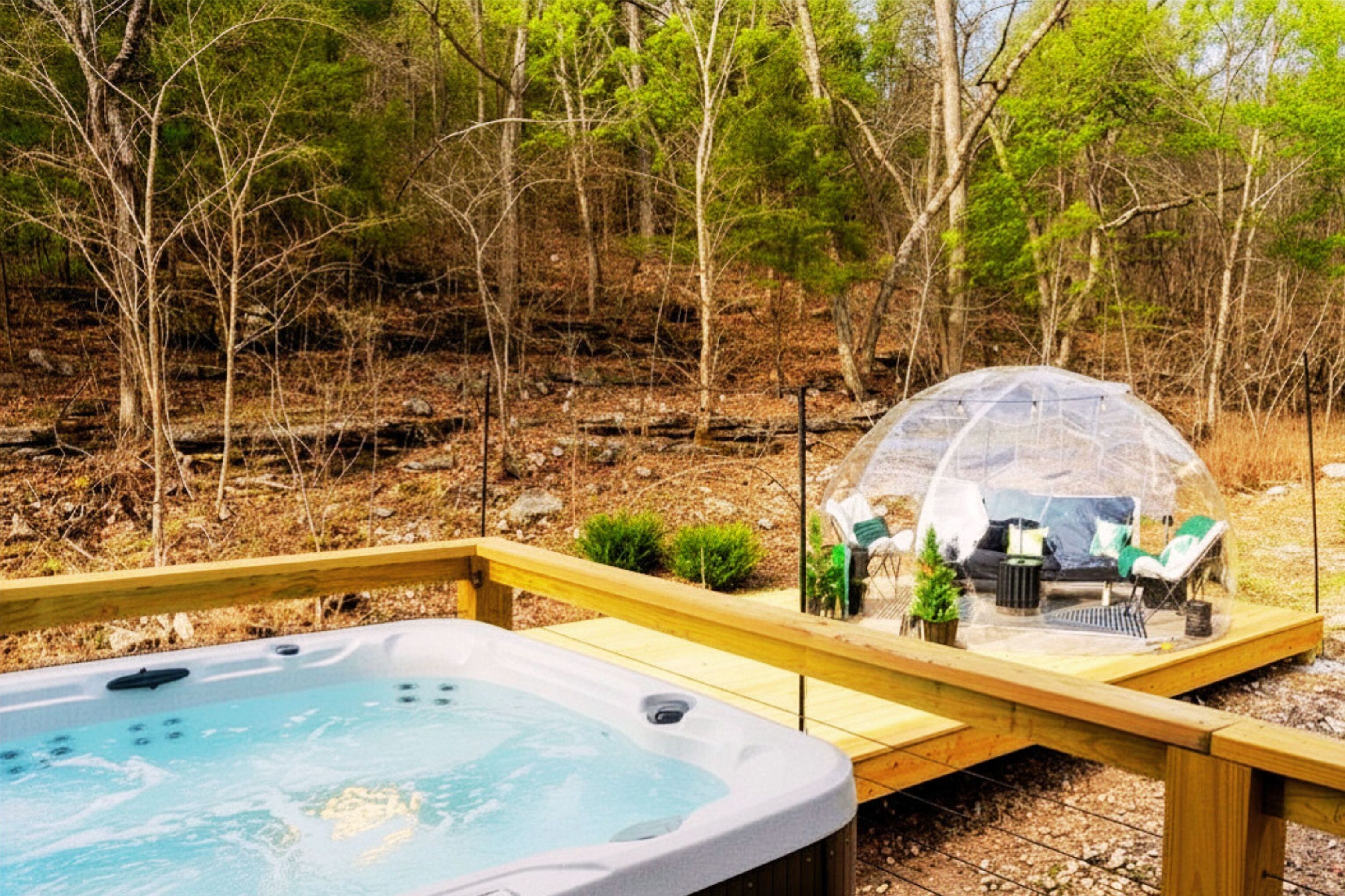 A hot tub with a wooden deck, surrounded by trees.