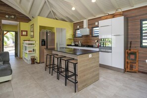 Una cocina moderna con una isla central, taburetes de bar, un refrigerador y un microondas.