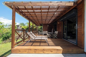 Un espace extérieur abrité doté d’un plancher en bois, d’une pergola et de sièges.