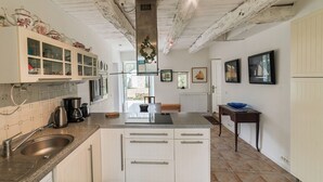 A kitchen with a central island, white cabinetry, a stainless steel sink, and a tiled backsplash.