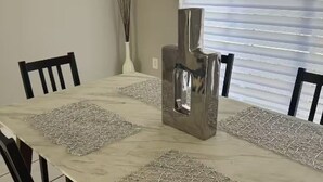 A dining table with a marble top, surrounded by four chairs, and a decorative metal sculpture in the center. - Miami Retreat with Backyard Pool (Miami)