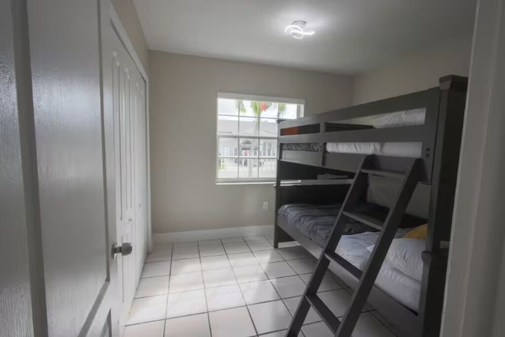 A room with bunk beds, a window, and a door.