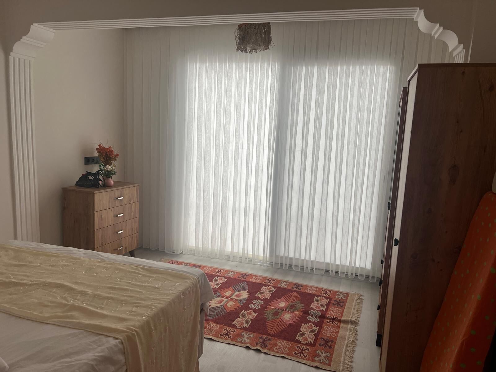 Une chambre à coucher avec un lit, une commode, un tapis et une porte.