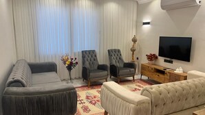 A living room with a sofa, two armchairs, a TV, and a decorative vase. - Fethiye  Merkezde Harika Ev (Fethiye)