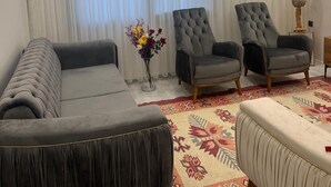 A living room with a sofa, two armchairs, a patterned rug, and a decorative vase with flowers. - Fethiye  Merkezde Harika Ev (Fethiye)