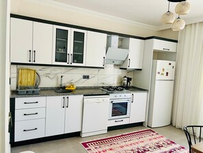Une cuisine moderne avec des meubles blancs, une cuisinière, un four et un réfrigérateur.