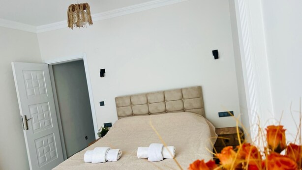 A bedroom with a bed, a door, and a wall-mounted light fixture. - Fethiye  Merkezde Harika Ev (Fethiye)