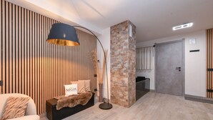 Ett modernt vardagsrum med en soffa, en lampa, en stenkupol och en vägg med träribbor.