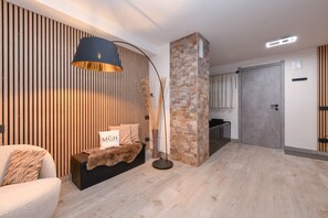 Ein modernes Wohnzimmer mit einer Couch, einer Lampe, einer Säule aus Stein und einer Wand aus Holzlamellen.