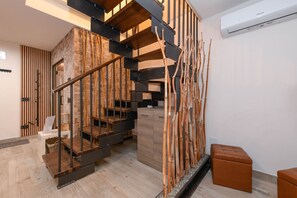 Eine moderne Treppe mit Holzstufen und Metallgeländern, eine kleine Holzbank und eine Wand-Klimaanlage.