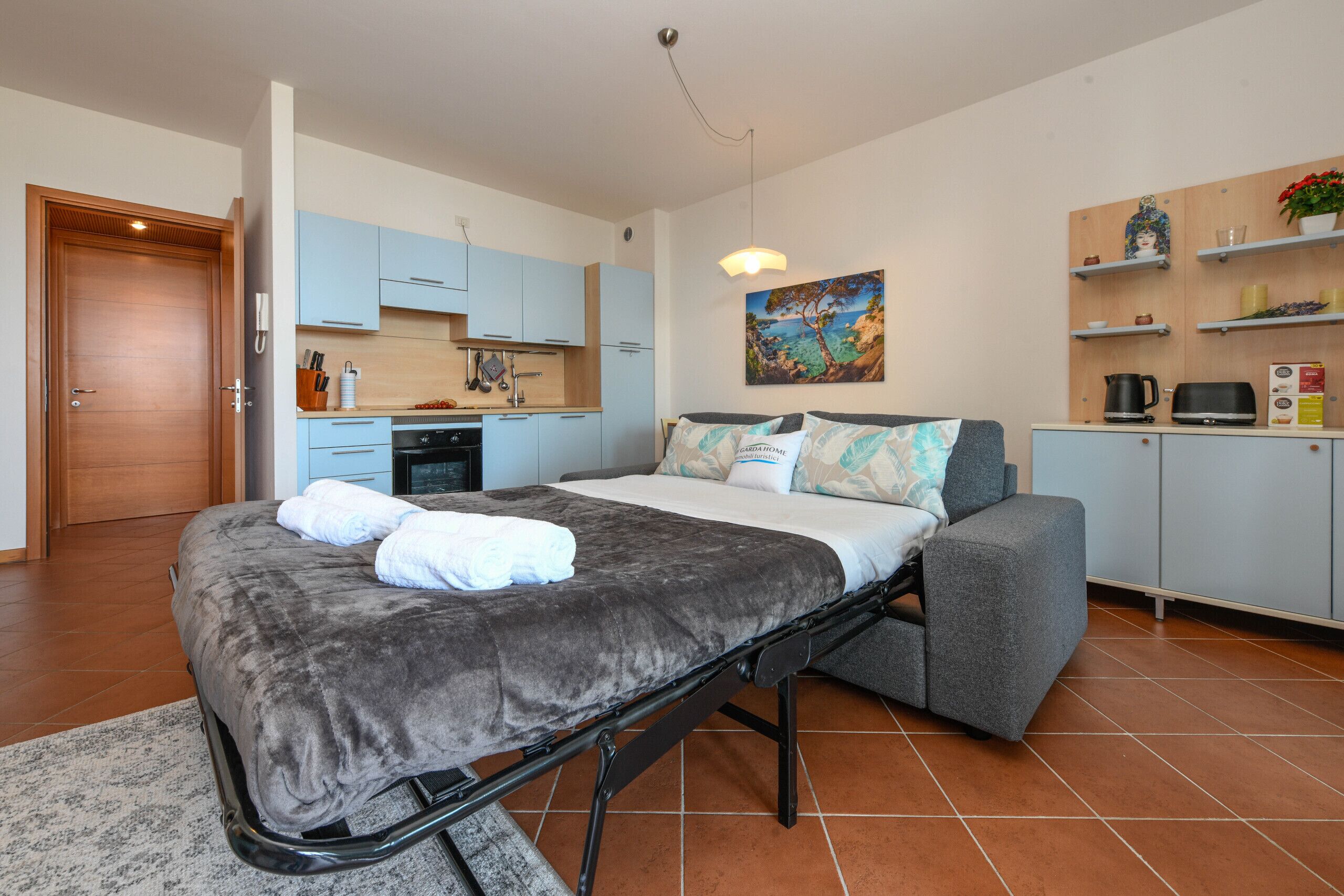 Un dormitorio con cama, sofá, zona de cocina y baño.