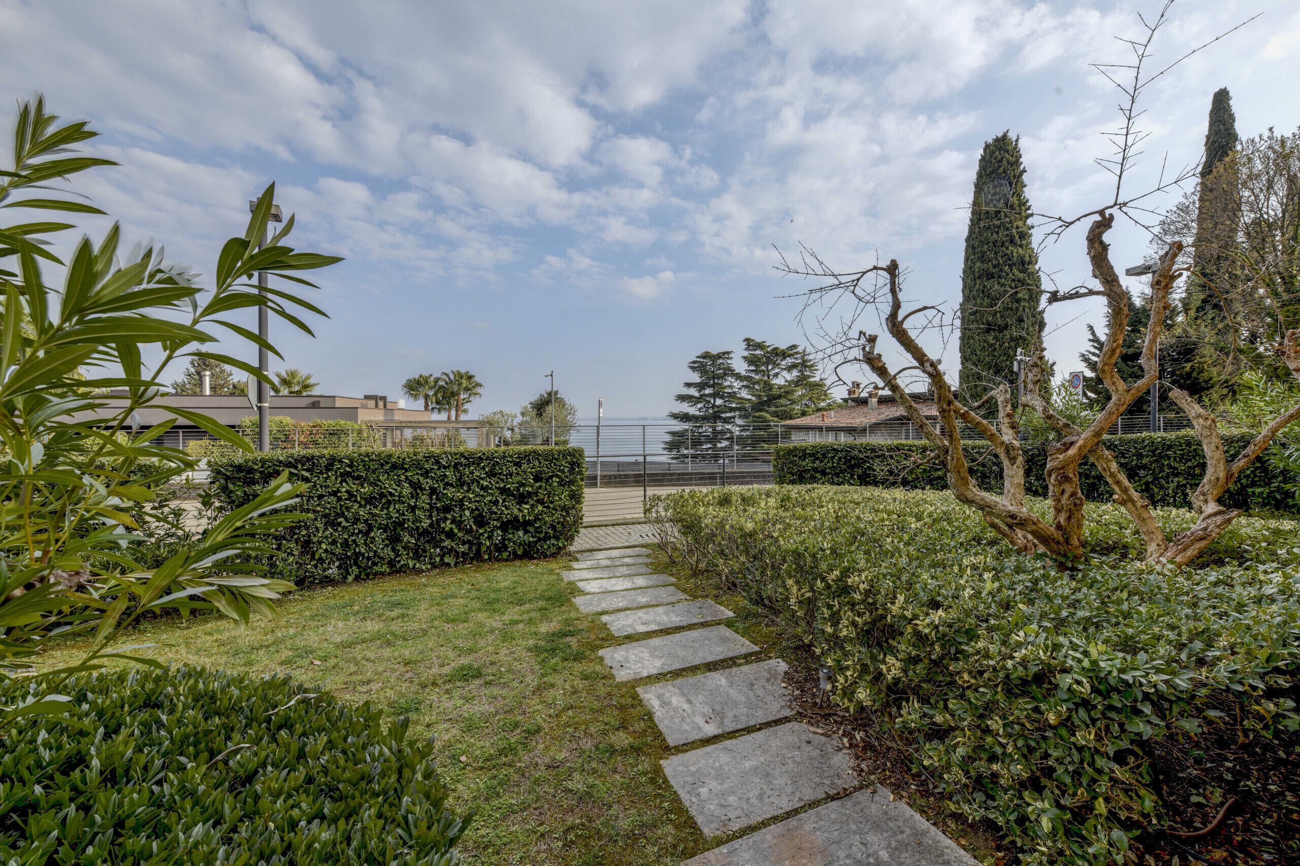 A pathway leading through a well-maintained garden with hedges and trees.