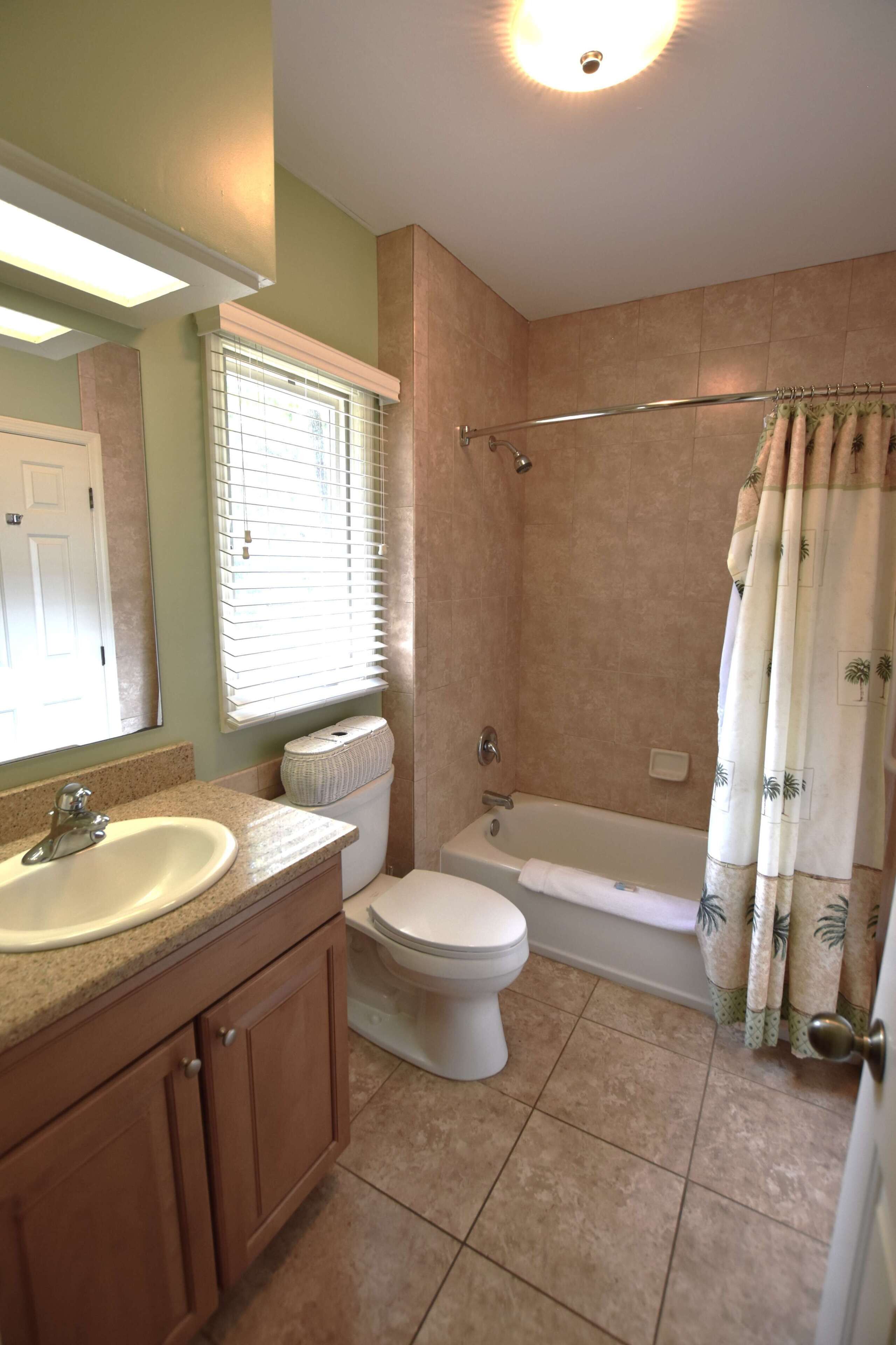 A bathroom with a sink, toilet, bathtub, and shower curtain.