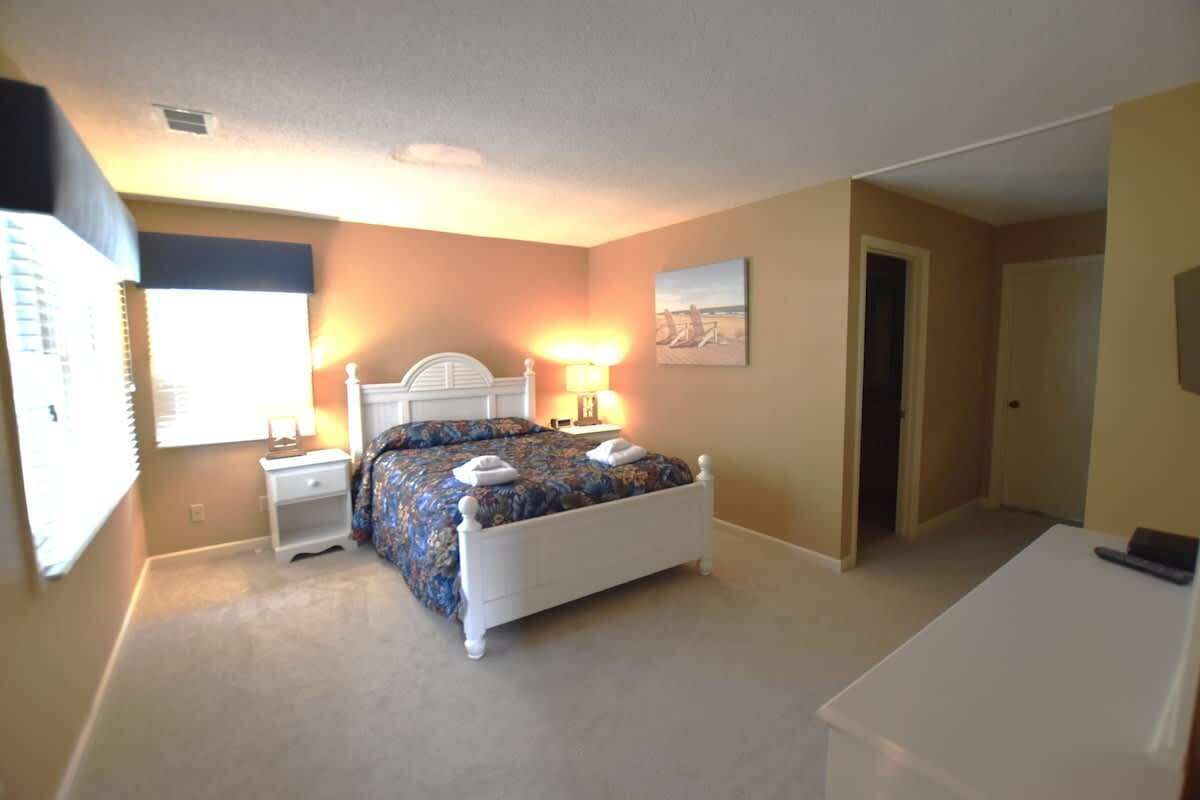 A bedroom with a bed, nightstands, a lamp, and a door.