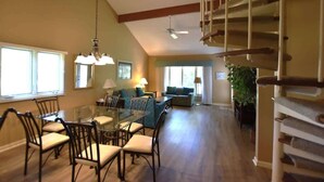 A spacious living area with a dining table, chairs, a sofa, and a staircase. - Golf, Beach, Pool & Biking, Relaxed Hilton Head Island Stay (Hilton Head Island)