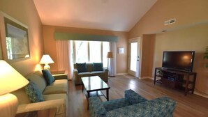 A living room with a sofa, armchairs, a coffee table, a television, and a window with curtains. - Golf, Beach, Pool & Biking, Relaxed Hilton Head Island Stay (Hilton Head Island)