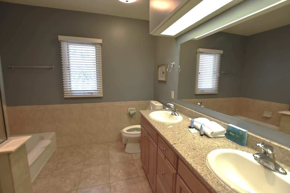 Une salle de bain avec deux lavabos, des toilettes et une baignoire.