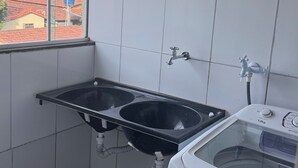 Una cocina pequeña con ventana, un lavabo y una lavadora.