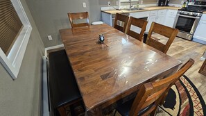 A dining area with a wooden table, chairs, and a kitchen in the background.