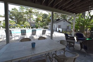A covered outdoor area with a pool, lounge chairs, and wicker furniture. - Brigantine Quarters Bliss, Scenic Shipyard, Pool & Beach Access (Hilton Head Island)