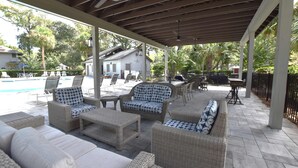 Un espace extérieur aménagé avec des meubles en osier, une piscine et une maison en arrière-plan.