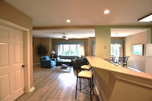 A kitchen with a bar area, a dining table with chairs, a sofa, and a ceiling fan. - Hilton Head Retreat, Pool, Golf, Beach Access (Hilton Head Island)