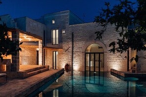 A modern building with a stone facade, a swimming pool, and a well-lit entrance. - Stunning superior mansion w/ pool in ancient town (San Cassiano)
