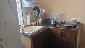 Uma cozinha compacta com bancada de mármore, pia, escorredor de louça, dispensador de água e uma balança.