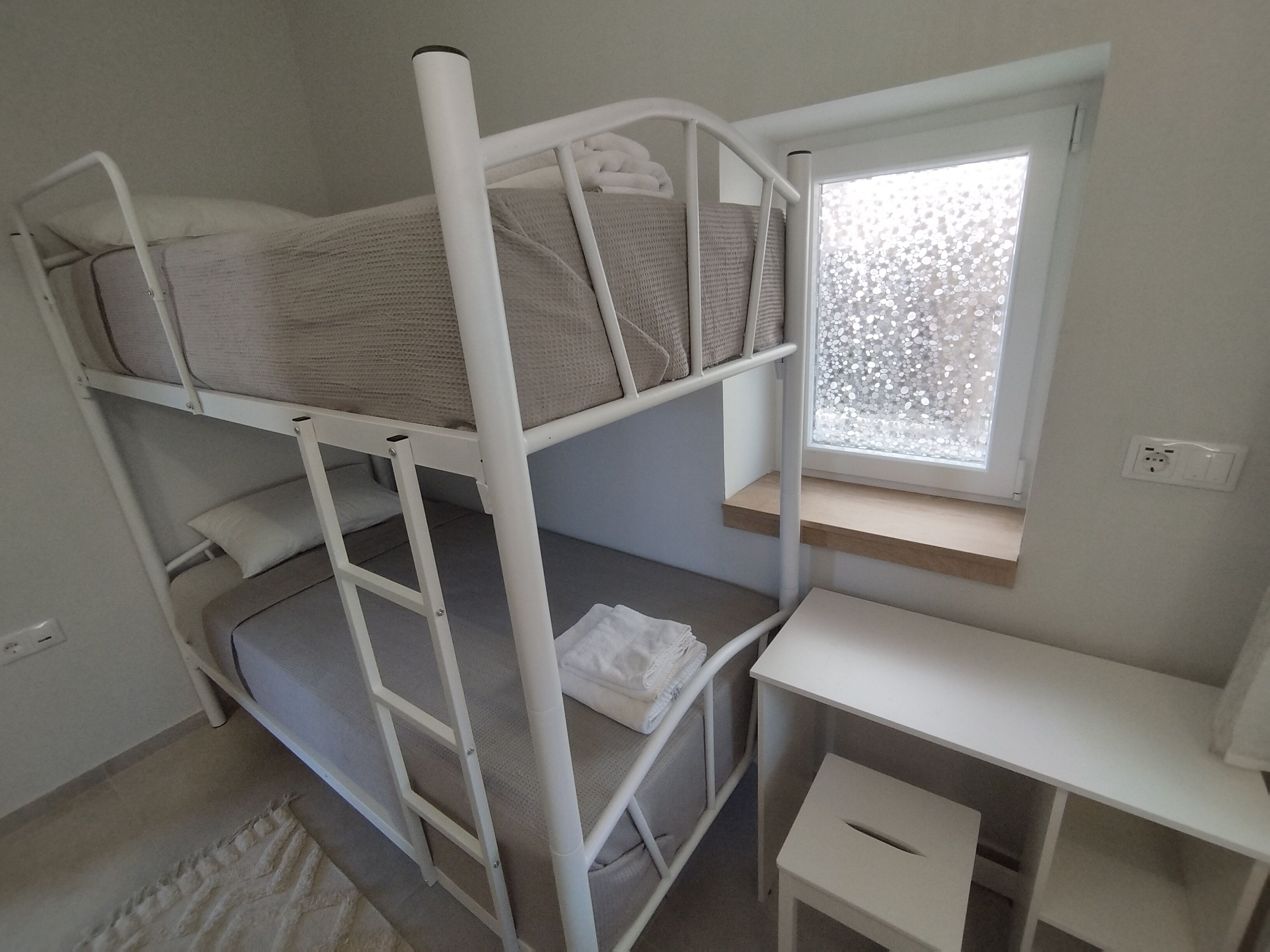 Een stapelbed met bureau en raam.