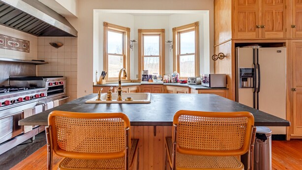 Una cocina con una isla central, armarios de madera, estufa y refrigerador.