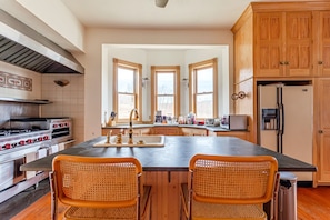 Una cocina con una isla central, armarios de madera, estufa y refrigerador.