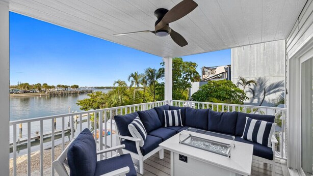A covered outdoor seating area with a view of a waterfront and palm trees. - Waterfront 3 Bedroom Condo with Beach Access Walkable to Everything. (Englewood)