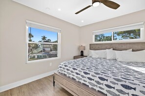 A bedroom with a bed, two windows, a ceiling fan, and a nightstand with a lamp. - Waterfront 3 Bedroom Condo with Beach Access Walkable to Everything. (Englewood)