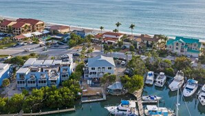 An aerial view of a coastal residential area with houses, a marina, and a beach. - Waterfront 3 Bedroom Condo with Beach Access Walkable to Everything. (Englewood)