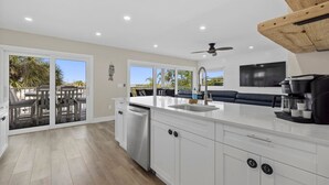 A modern kitchen with a large island, a built-in dishwasher, and a coffee maker. - Waterfront 3 Bedroom Condo with Beach Access Walkable to Everything. (Englewood)