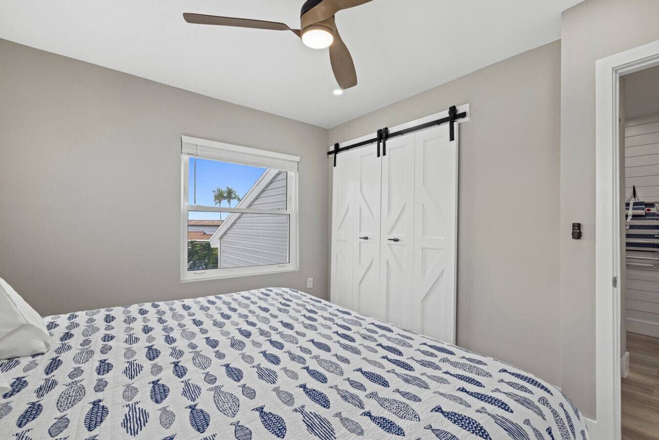 A bedroom with a bed, a ceiling fan, a window with blinds, and a closet with sliding doors.