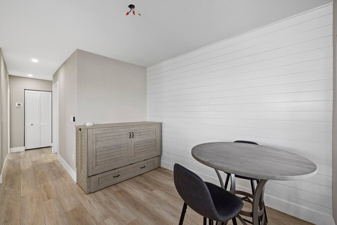Ein Zimmer mit einem Holzkasten, einem runden Tisch und zwei Stühlen.