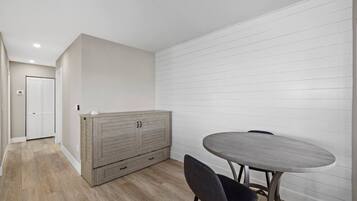 Ein Zimmer mit einem Holzkasten, einem runden Tisch und zwei Stühlen.