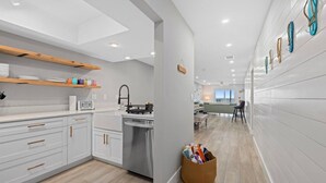 A modern kitchen with white cabinets, a wooden shelf, and a dish rack. - Beachfront Condo on Manasota Key (Englewood)