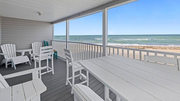 A covered deck with white furniture, overlooking a beach. - Beachfront Condo on Manasota Key (Englewood)