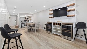 A modern kitchen with a dining area, a TV mounted on the wall, and a wine rack. - Beachfront Condo on Manasota Key (Englewood)