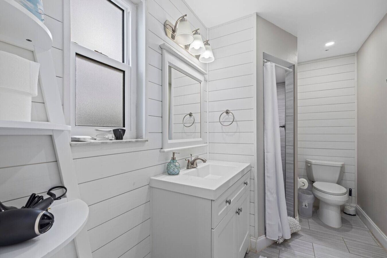 A modern bathroom with white cabinetry, a vanity with a mirror, a sink, and a toilet.