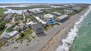 An aerial view of a coastal residential area with beachfront properties, a marina, and a clear view of the ocean. - Beachfront Condo on Manasota Key (Englewood)