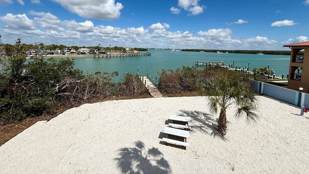 A beach with a clear view of the water, a wooden walkway, and a palm tree. - Waterfront Condo w/Private Beach on Manasota Key! (Englewood)