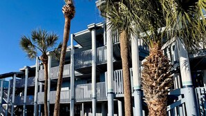 A multi-story building with balconies, palm trees, and a clear blue sky. - Waterfront Condo w/Private Beach on Manasota Key! (Englewood)