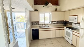 A kitchen with a dishwasher, stove, microwave, and a large window. - Waterfront Condo w/Private Beach on Manasota Key! (Englewood)