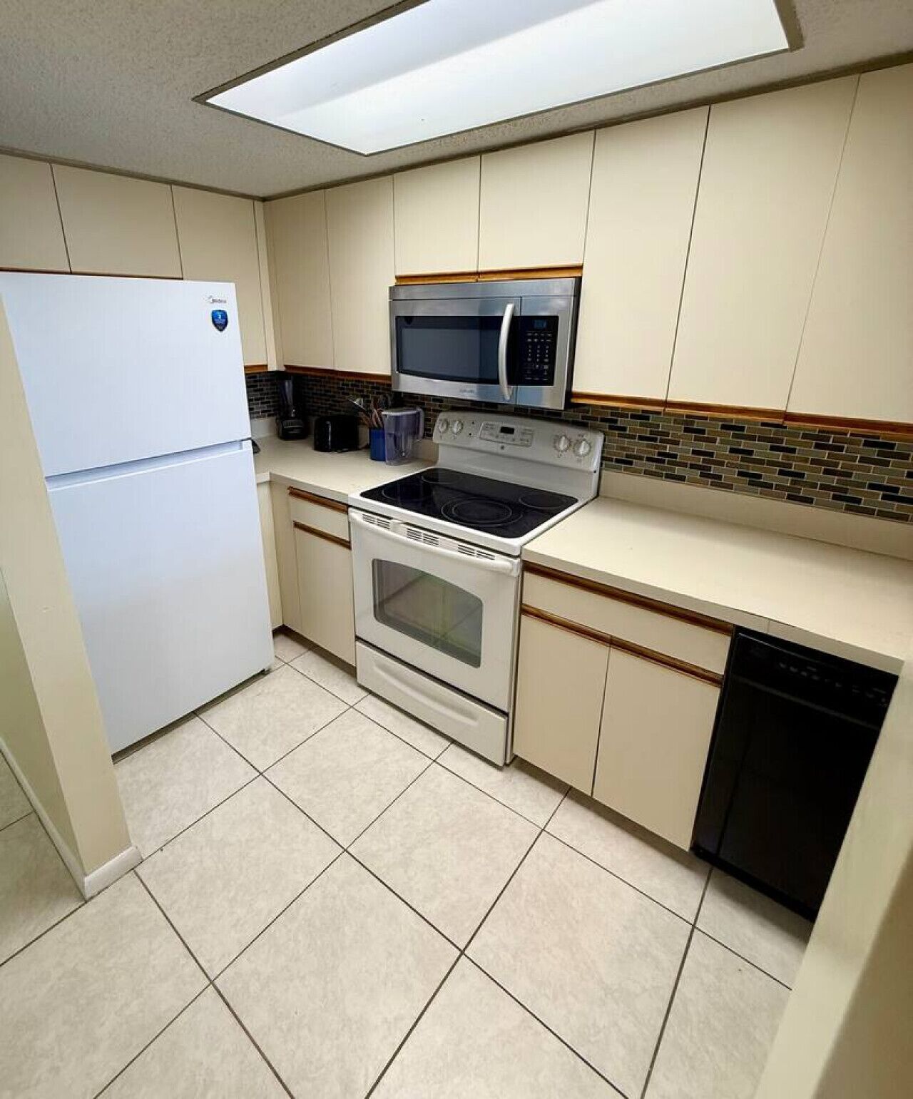 A kitchen with a refrigerator, microwave, stove, oven, and dishwasher.