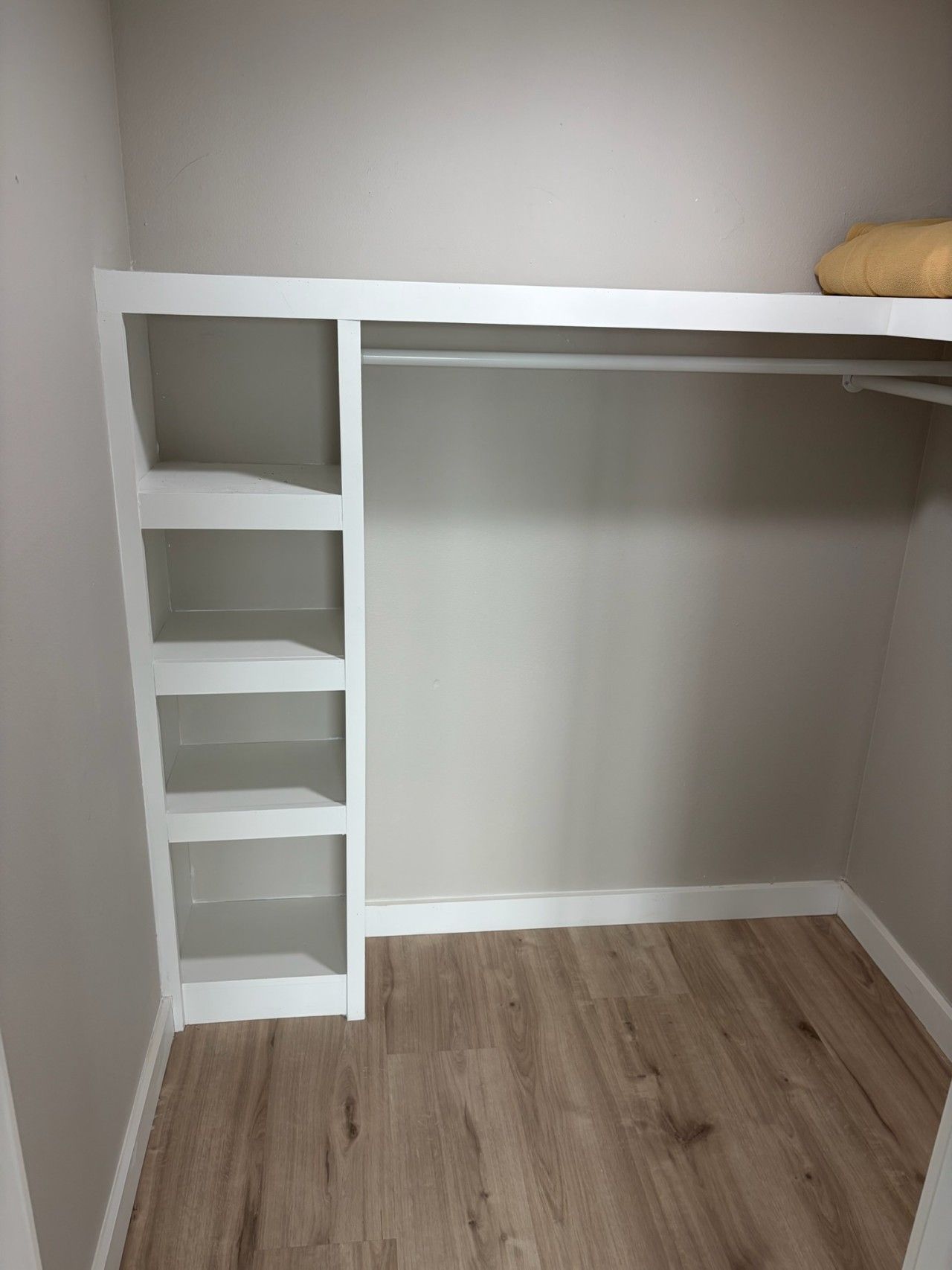 Ein Schrank mit weißen Regalen und Holzboden.