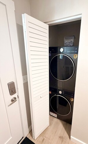 Een wasserette met een witte deur, een wasmachine en een droger.