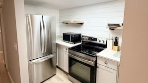 Una cocina moderna con electrodomésticos de acero inoxidable, microondas, estufa y armarios blancos.